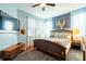 Comfortable bedroom featuring a ceiling fan, a mounted TV, and stylish decor on pale-blue walls at 14320 Tree Swallow Way, Lakewood Ranch, FL 34202