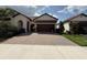 Close up of the house featuring a tile roof, arched entry, brick driveway, and manicured landscaping at 17304 Scuba Crest St, Wimauma, FL 33598
