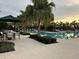 Large swimming pool with seating areas, palm trees and a beautiful sunset in the background at 17304 Scuba Crest St, Wimauma, FL 33598