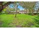 This backyard, framed by trees, features a view of the screened-in pool area and the home's facade at 17802 Mission Oak Dr, Lithia, FL 33547