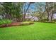 Single-story home with beautifully landscaped yard, featuring mature trees and green lawn at 17802 Mission Oak Dr, Lithia, FL 33547