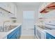 Cozy kitchen with white appliances, blue and white cabinetry and double stainless steel sink at 1799 N Highland Ave # 185, Clearwater, FL 33755