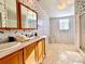 Well-lit bathroom featuring a double vanity, decorative wallpaper, and a shower-tub combination at 250 S Port Royal Ln, Apollo Beach, FL 33572