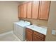 Well-lit laundry room includes washer, dryer, wash basin, and plenty of cabinet space at 2527 Terracina Dr, Venice, FL 34292