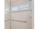 Glass-enclosed shower featuring tiled walls and grab bars at 2609 Rosehaven Dr, Wesley Chapel, FL 33544
