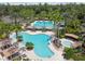 An aerial view of a lagoon style community pool with lounge seating and multiple swimming areas surrounded by palm trees at 2609 Rosehaven Dr, Wesley Chapel, FL 33544