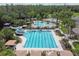 Aerial view of a community pool complex with swimming lanes, a waterslide, lounge areas, and lush landscaping at 2609 Rosehaven Dr, Wesley Chapel, FL 33544