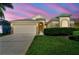 A single-story home with a two-car garage, decorative stone accents, manicured lawn, and shrubbery at 2609 Rosehaven Dr, Wesley Chapel, FL 33544
