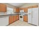 Well-lit kitchen features wood cabinetry, white appliances, and tile flooring for easy maintenance at 2609 Rosehaven Dr, Wesley Chapel, FL 33544