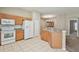 Large kitchen with wood cabinets, white appliances and tile floors with entry into a carpeted living space at 2609 Rosehaven Dr, Wesley Chapel, FL 33544