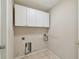 Functional laundry room with overhead cabinets, tile flooring, and utility connections at 2609 Rosehaven Dr, Wesley Chapel, FL 33544