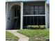 Condo exterior featuring a stairway leading to units, complemented by green grass and manicured shrubs at 2699 Pine Ridge E Way # H2, Palm Harbor, FL 34684