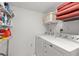 Functional laundry room with modern washer and dryer units, plus shelving for storage and supplies at 2699 Pine Ridge E Way # H2, Palm Harbor, FL 34684