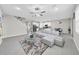 Open-concept living area featuring gray tile flooring, a modern couch, and seamless access to the kitchen at 32136 Conchshell Sail St, Wesley Chapel, FL 33545