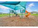 Vibrant, covered playground featuring a slide, climbing structures, and safe wood chip ground cover at 32136 Conchshell Sail St, Wesley Chapel, FL 33545