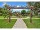 Inviting playground entrance with a wooden pergola and paved walkway in a grassy, tree-lined park at 32136 Conchshell Sail St, Wesley Chapel, FL 33545