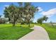 Scenic view of a paved walking path winding through a lush park with large, shade-providing trees at 32136 Conchshell Sail St, Wesley Chapel, FL 33545