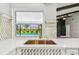 Kitchen sink with white cabinets, quartz countertops, decorative backsplash, and view of the backyard pool at 325 Gladstone Blvd, Englewood, FL 34223