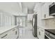 Bright kitchen featuring white cabinets and stainless steel appliances, leading into a living area at 325 Gladstone Blvd, Englewood, FL 34223