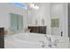 Luxurious soaking tub in the bathroom with dual faucet and beautiful oversized mirrors over dark wood cabinets at 3559 Maple Bay Ln, Land O Lakes, FL 34638
