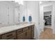 Bright bathroom featuring quartz countertop, wood cabinets, and mirror with a view into another room at 3559 Maple Bay Ln, Land O Lakes, FL 34638