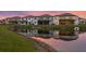 Back exterior view of townhomes along the pond featuring a tranquil water view at sunset at 3559 Maple Bay Ln, Land O Lakes, FL 34638