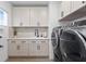 The laundry room has white cabinets and counter space, decorative backsplash, and front loading washer and dryer at 3559 Maple Bay Ln, Land O Lakes, FL 34638