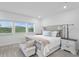 Bright main bedroom with a tufted bed, stylish side tables, and plenty of natural light from large windows at 3559 Maple Bay Ln, Land O Lakes, FL 34638
