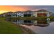 View of back exteriors of homes reflecting in the pond at sunset at 3559 Maple Bay Ln, Land O Lakes, FL 34638