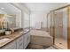 Bathroom featuring a soaking tub, shower with gold trim, and a double vanity with a granite countertop at 3633 Morgans Bluff Ct, Land O Lakes, FL 34639
