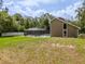 A spacious backyard showcasing the screened-in pool area with a manicured lawn and mature trees at 4044 Red Fox Ct, Wesley Chapel, FL 33543