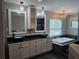This bathroom features a double sink vanity, white cabinetry, and a luxurious soaking tub with black tiled surround at 4044 Red Fox Ct, Wesley Chapel, FL 33543