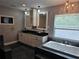 A luxurious bathroom featuring double sinks, white cabinetry, a chandelier, and a soaking tub under a window at 4044 Red Fox Ct, Wesley Chapel, FL 33543