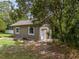Back exterior view of a neutral-colored, single-story home surrounded by lush trees and grass at 4044 Red Fox Ct, Wesley Chapel, FL 33543