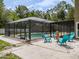 Inviting screened-in pool area with comfortable seating and a serene atmosphere surrounded by mature trees at 4044 Red Fox Ct, Wesley Chapel, FL 33543