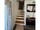 A carpeted staircase with white risers and wood treads ascends past a living area with a TV and decorative screen at 4304 Harbor House Dr, Tampa, FL 33615
