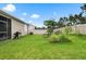 Spacious backyard with lush green grass, privacy fence, small garden plots, and an outdoor grill at 5006 Jackel Chase Dr, Wimauma, FL 33598