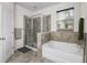 Inviting bathroom featuring a glass enclosed shower, tub, and tile detail providing spa-like retreat at 5006 Jackel Chase Dr, Wimauma, FL 33598