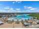 Aerial view of a community pool with beach entry, lounge chairs, umbrellas, and white buildings on a clear day at 5006 Jackel Chase Dr, Wimauma, FL 33598