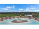 Aerial view of a community pool with beach entry, lounge chairs, umbrellas, and white buildings on a clear day at 5006 Jackel Chase Dr, Wimauma, FL 33598