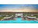 Aerial view of a luxurious community pool with seating areas, cabanas, palm trees, and manicured landscaping at 5006 Jackel Chase Dr, Wimauma, FL 33598