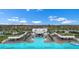 Aerial view of a luxurious community pool with seating areas, cabanas, palm trees, and manicured landscaping at 5006 Jackel Chase Dr, Wimauma, FL 33598