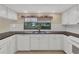 A well-lit kitchen features white cabinetry, a dark countertop, and a garden view at 5078 Florentine Ct, Spring Hill, FL 34608