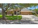 Charming single-story home with manicured lawn, mature trees, and a three-car garage on a sunny day at 5519 Reflections Blvd, Lutz, FL 33558