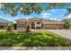 Well-maintained single-story house featuring lush green lawn, landscaping, and a three-car garage at 5519 Reflections Blvd, Lutz, FL 33558