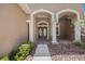 Home entrance featuring double doors with glass panels, white columns, and well-maintained landscaping at 5519 Reflections Blvd, Lutz, FL 33558