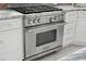 Close-up of a Wolf range and oven, complemented by white cabinets and granite countertops at 5782 Westshore Dr, New Port Richey, FL 34652