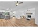Spacious living room featuring a white brick fireplace, wood floors, ceiling fans, and stainless steel refrigerator at 5927 10Th N St, St Petersburg, FL 33703