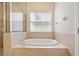 Bathroom featuring tiled tub, a window with blinds, and neutral paint at 6625 Interbay Blvd, Tampa, FL 33611