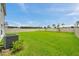 Large, green backyard is fenced in, and contains a small shrub and HVAC unit at 7641 Sail Clover Ln, Zephyrhills, FL 33540